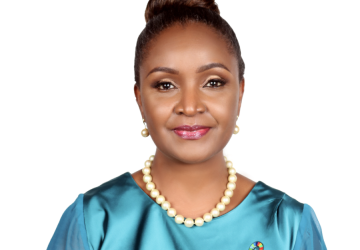 Una mujer con un vestido azul claro y el pelo recogido en un moño sonríe a la cámara.