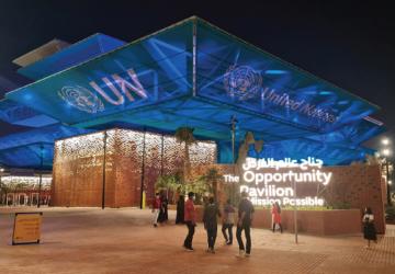Una foto del exterior del centro de exposiciones, mostrando a la gente en el exterior por la noche con un texto proyectado en el edificio.