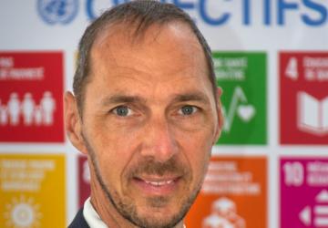 رجل يقف أمام لافتة عليها شعارات أهداف التنمية المستدامة