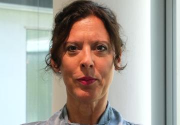 امرأة ترتدي قميصًا أزرق اللون وتبتسم للكاميرا.