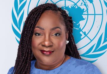 Woman in blue shirt standing in front of the UN logo