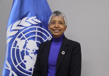 Woman in a suit in front of a UN flag