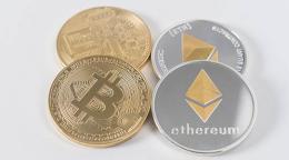 Photographie montrant quatre pièces rondes ressemblant à des pièces de monnaie, deux portant le symbole du Bitcoin et les deux autres celui de l'Ether.