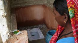 Une femme népalaise se tient debout près des toilettes construites dans son village.