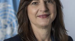 official photo of Susana Sottoli shows her standing in front of the UN flag.