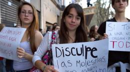 تحمل ثلاث متظاهرات لافتات أمام الكاميرا.