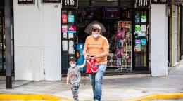 Un homme et un petit garçon sortent d'un magasin. Ils portent tous deux un masque de protection.