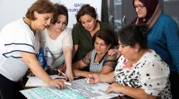 Seis personas trabajando en un material sobre una mesa.