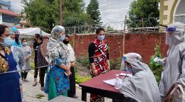 Plusieurs femmes, dont Mithu Tamang, font la queue pour faire vérifier leur température par le personnel féminin d’un centre d’hébergement pour femmes en quarantaine géré par l’association "Women for Human Rights". Les femmes portent toutes un masque de protection, tandis que les membres du personnel de l’association portent également un équipement de protection individuelle et une visière de protection.