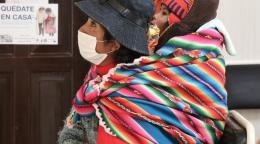 Une femme bolivienne vêtue une tenue traditionnelle et portant un enfant sur le dos patiente dans le centre de santé Los Pinos dans le district de Senkata, à El Alto, en Bolivie.
