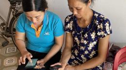 Mrs. Man (right) learns from Viettel Pay staff how to use e-payment technology on her phone to receive Government’s Social Assistance package for COVID-19