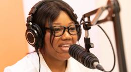 Une jeune femme équipée d’un casque s’exprime au micro d'une chaîne de radio.