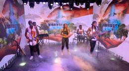 La chanteuse zimbabwéenne Caroleen Masawi et son groupe se produisent sous les projecteurs dans un décor de panneaux sur lesquels figurent des images de la nature ainsi que le mot "Biodiversité", en anglais.