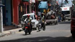 A city scene of motorcyclist driving down a road.