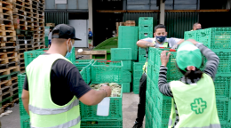 Les employés du marché central, considérés comme des personnels essentiels, s’activent autour du déchargement des caisses de marchandises pendant la pandémie de COVID-19. Ils portent tous un masque de protection.
