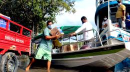 رجل يسير على الشاطئ بالقرب من قارب وهو يحمل المساعدات من موظفي المنظمة الدولية للهجرة.