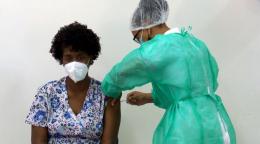 Ana Manuela, a health technician, sits patiently as she receives the COVID-19 vaccine.