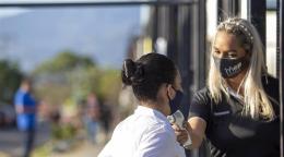 معلمة تفحص درجة حرارة الفتاة قبل دخول المدرسة عند البوابة.