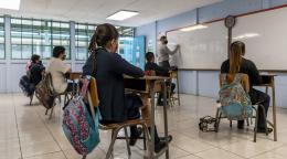 تلاميذ يرتدون كمامات ويجلسون على مقاعد داخل الصف.