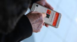 Close-up of the hands of a senior person who is holding a cell phone and using an application.