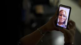 An image of a person's hand holding a cellphone with another person