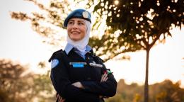 Captain Ahlam Al-Habahbeh proudly wearing her uniform poses for the camera outside standing near a tree. 