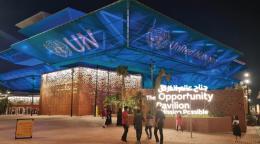 Una foto del exterior del centro de exposiciones, mostrando a la gente en el exterior por la noche con un texto proyectado en el edificio.