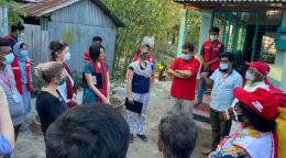 مجموعة كبيرة من الأشخاص يرتدون كمامات ويقفون في الخارج على شكل دائرة.