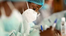 Un primer plano de una trabajadora sanitaria con equipo de protección mientras toma notas.