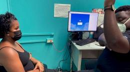 A nurse shows a woman sitting on a chair where her implant will be placed on her arm.