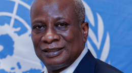 Photo d'Edward Kallon, le nouveau Coordonnateur résident des Nations Unies au Zimbabwe. M. Kallon est habillé en costume cravate bleu et se tient devant le drapeau des Nations Unies.