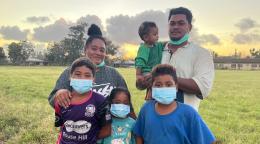 A family of six stand outside during sunset. 