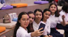 Five girls take a selfie together on a cell phone. 