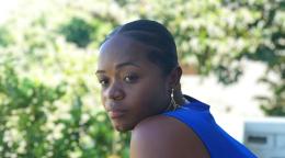 A woman in a blue tank top gazes outwards. 