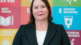 امرأة تقف أمام لافتة عليها شعارات أهداف التنمية المستدامة.