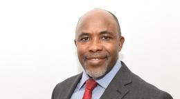 A man in a red tie smiles for the camera.