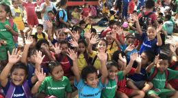 أطفال يرتدون ملابس ملونة يرفعون أيديهم في الهواء.