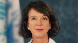 تقف المنسقة المقيمة المعينة حديثًا في كوسوفو أمام علم للأمم المتحدة.