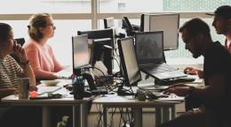 A group of people work on their computers in an office.