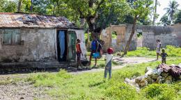 فتاتان تتحدثان عند مدخل منزل قديم متهدم تحيط به الأشجار.