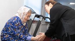 Two women holding hands side by side, one in black and one in blue with a headscarf