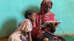 Girls use a solar-powered tablet at an e-learning centre in Jabalain, Sudan.