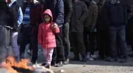 Child in a pink jacket holding on to her father