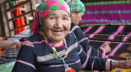 Woman in a colourful traditional dress and headscarf smiling at the camera