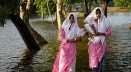 Unas niñas vadean las aguas de la inundación de camino a la escuela en Sunamganj, Bangladesh.
