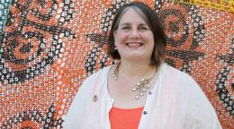 Woman in a white and orange shirt against a colourful printed background