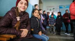 A group of children is jackets and winter clothes stand in a school classroom