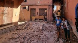 Two young people walk through a crumbled building after the earthquake in Morocco