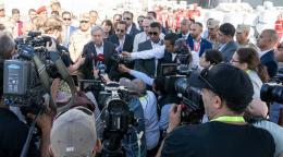 UN officials and security stand around microphones and speak to media and members of the press.