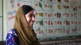 woman in brown head scarf smiles side on the camera